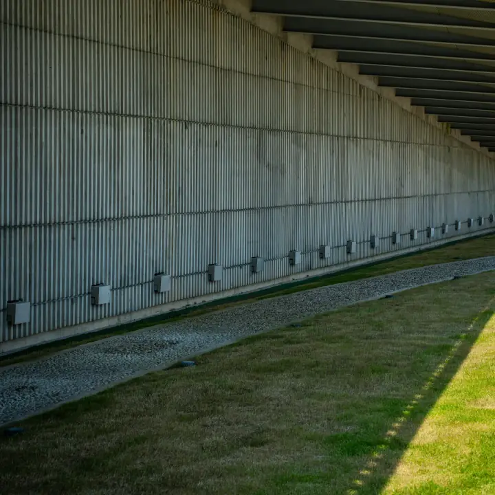 Mur de béton strié et ligne d'ombre nette sur la pelouse