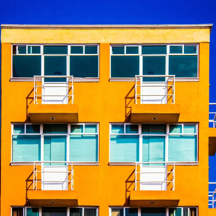 Balcons répétés d'un immeuble orange sur fond de ciel bleu intense