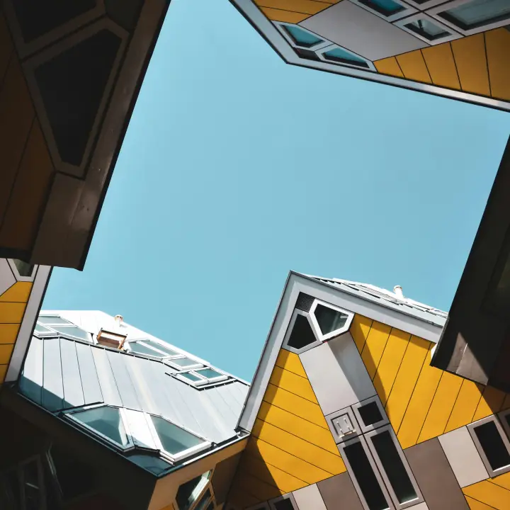 Contre-plongée entre des maisons cubiques jaunes vers le ciel bleu