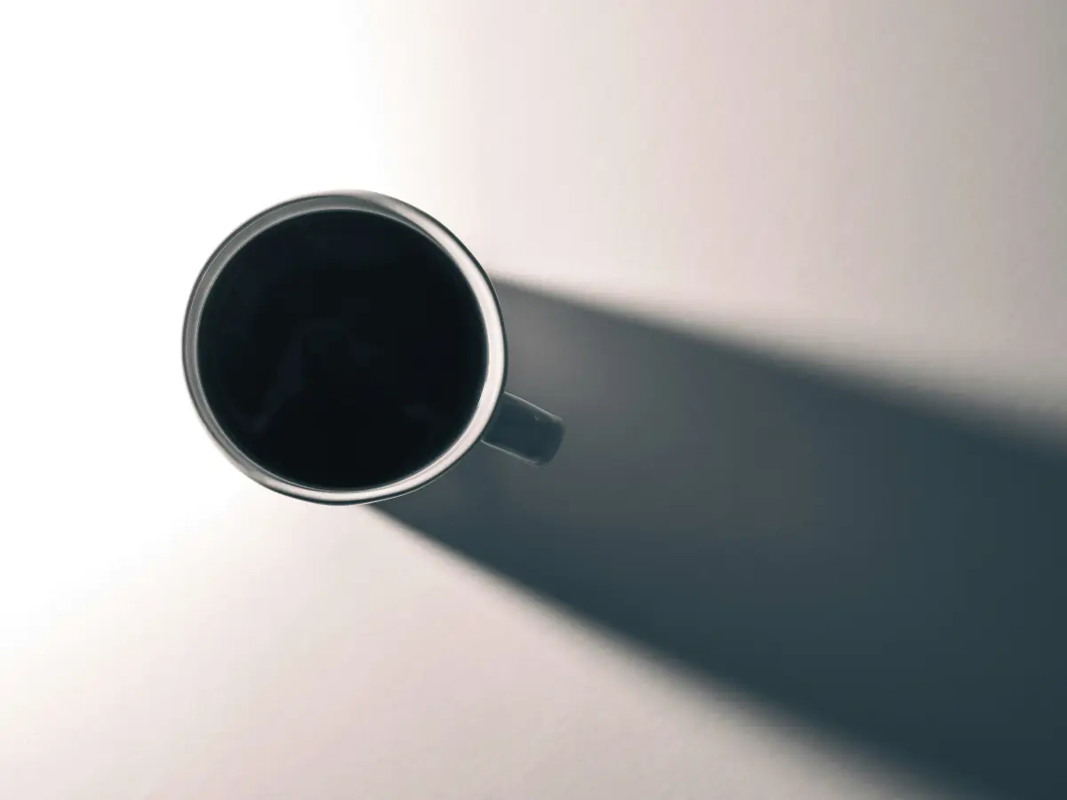 Tasse de café vue de haut projetant une longue ombre