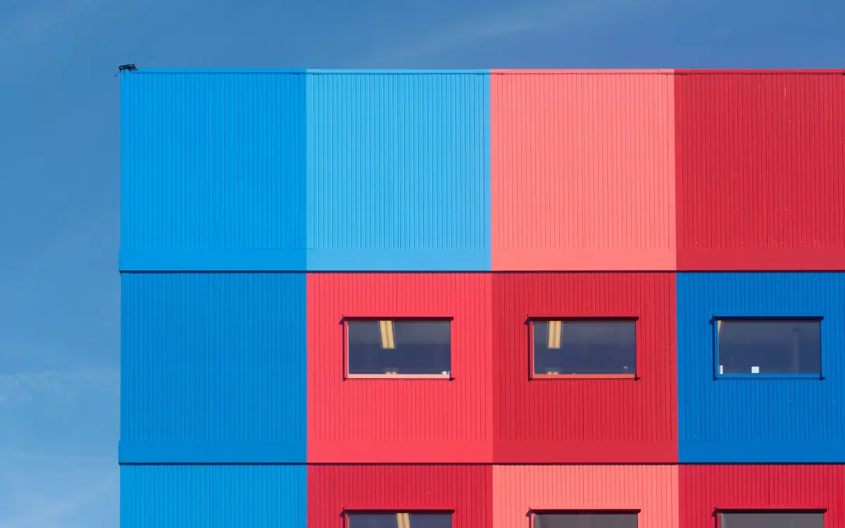 Façade modulaire en blocs rouges et bleus sous un ciel bleu