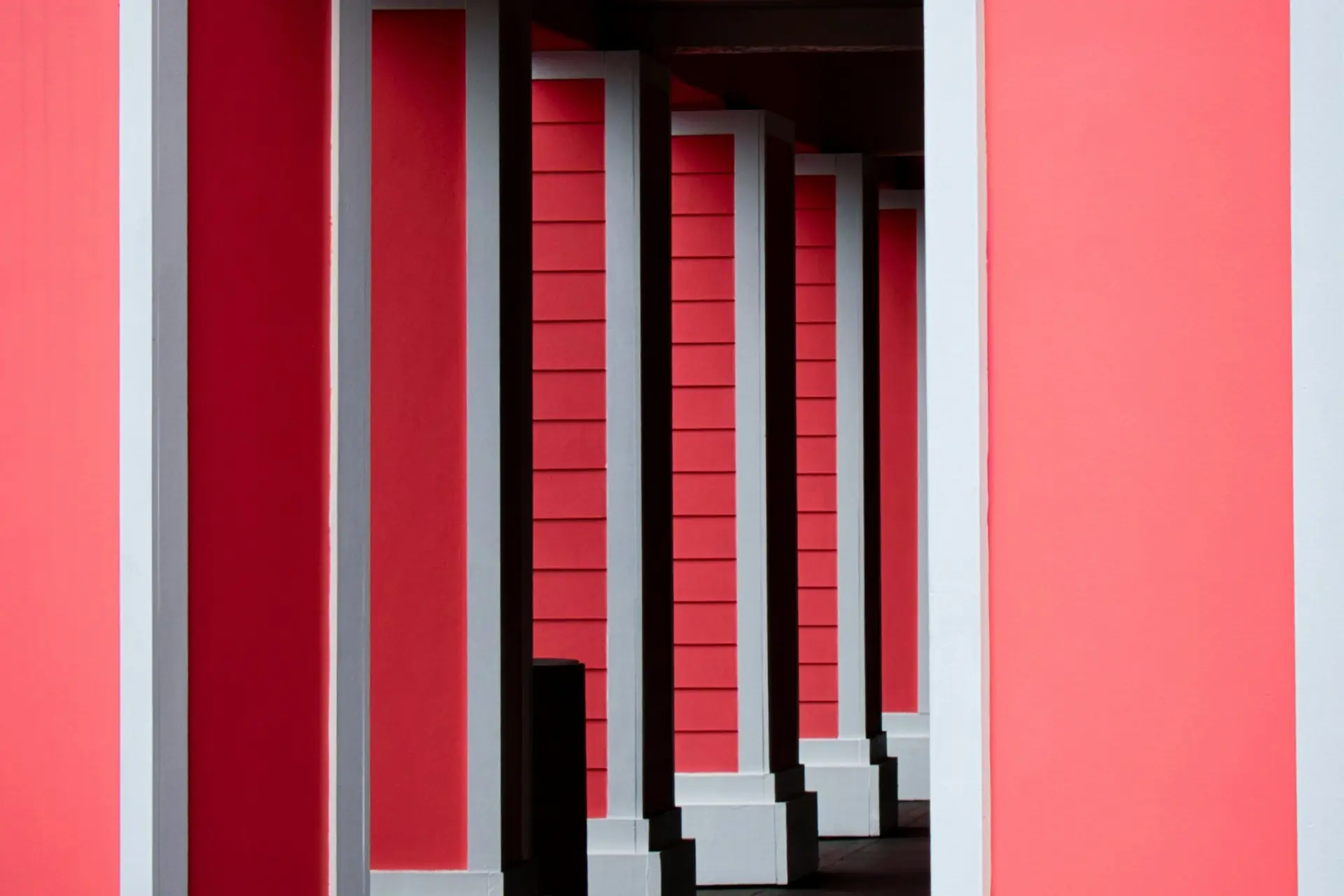 Colonnade rouge et blanche en perspective, ombre calme