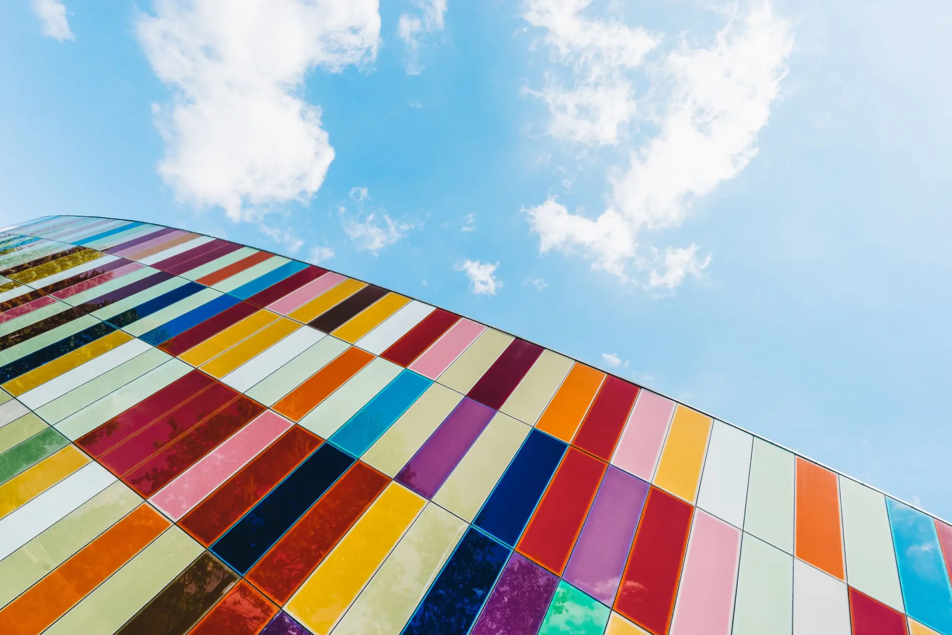 Façade courbe de panneaux de verre multicolores vue en contre-plongée, ciel bleu