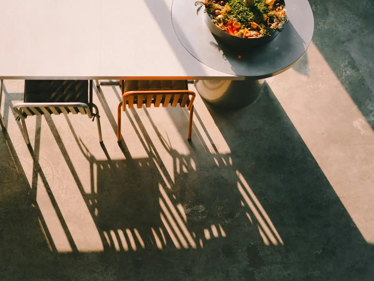 Terrasse ensoleillée : table et chaises projetant des ombres rayées